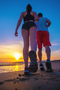男人和女人在日落时分在地处热带的海滩上运行