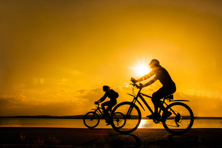 空的空间。运动的朋友在自行车在日落。骑自行车的人沿着海岸。体育在自然背景