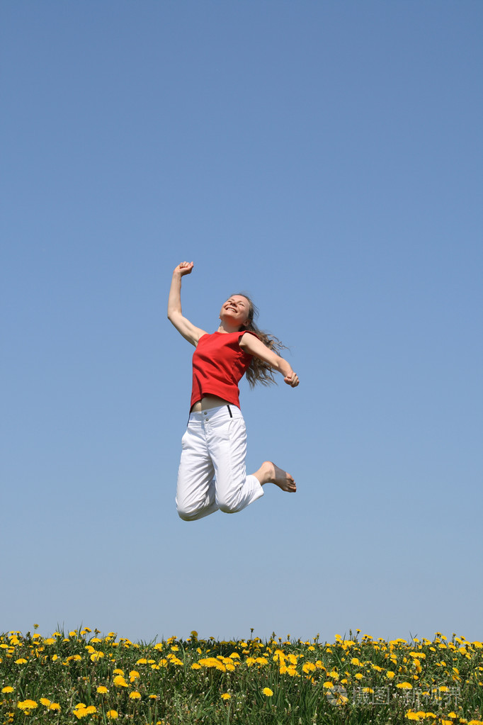 微笑快乐女孩跳在开花字段中
