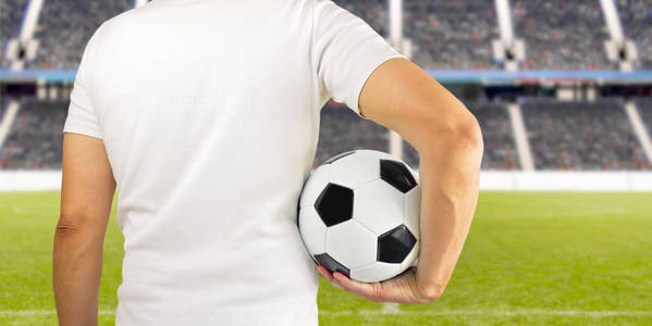 一名年轻球员在体育场的怀抱中手持足球的画面。后视镜