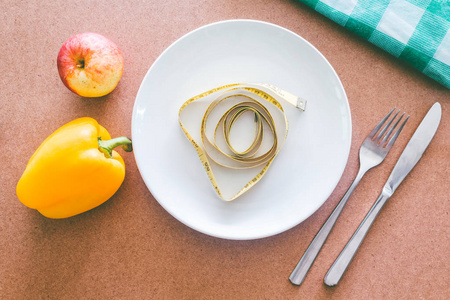 木桌上的空盘子叉子刀和卷尺健康食品概念