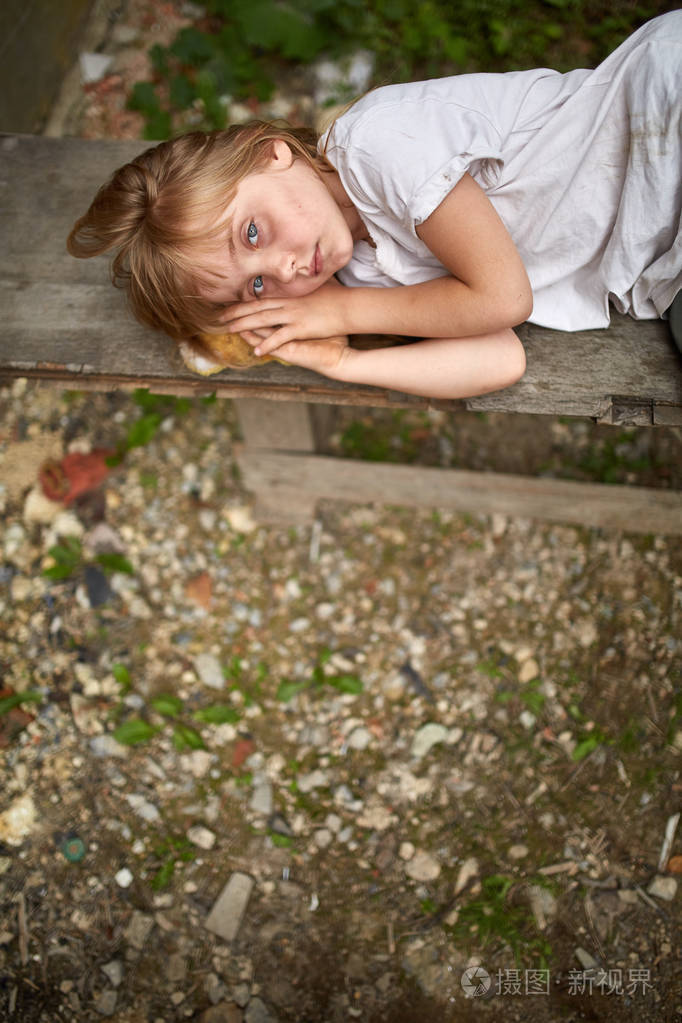 不幸的流浪孩子的肖像躺在黑板上肮脏的小巷, 浅景深, 垂直
