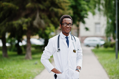时尚的非洲裔美国医生与听诊器和实验室大衣, 在眼镜摆在室外