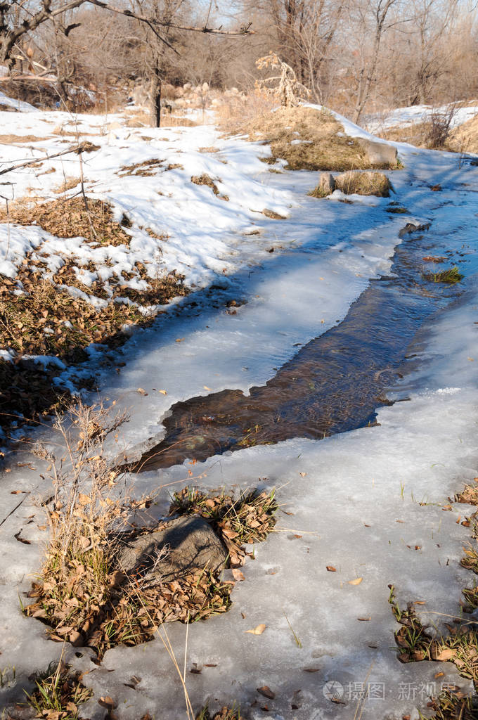在早春流在一条小河的水.春景.山风景用冰冻的小溪