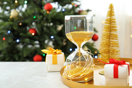 沙漏与礼物和节日装饰在桌上。圣诞节倒计时