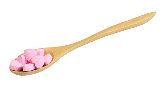 保健概念, 木勺满粉红色的心脏形状的维生素丸隔离在白色的背景