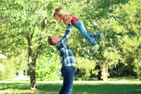 快乐的父亲和女儿在绿色公园里玩耍