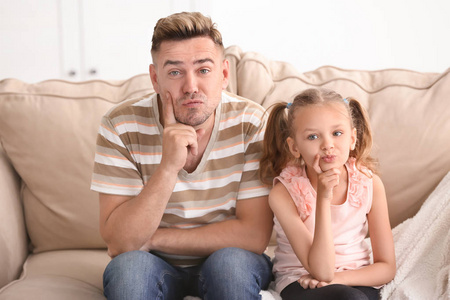 滑稽的父亲和女儿坐在沙发在家