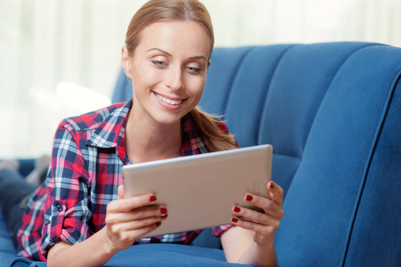 年轻白种人女人在她的客厅里阅读数字平板电脑在家里上网冲浪互联网和工作