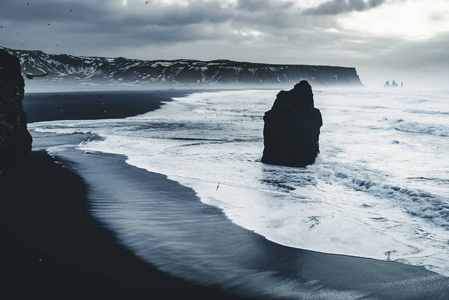 在冰岛著名的黑色沙滩 Reynisfjara 日出。刮风的早晨。海浪。五彩缤纷的天空。早晨日落