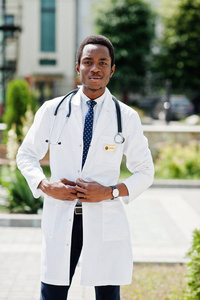 时尚的非洲裔美国医生与听诊器和实验室大衣摆在医院后院