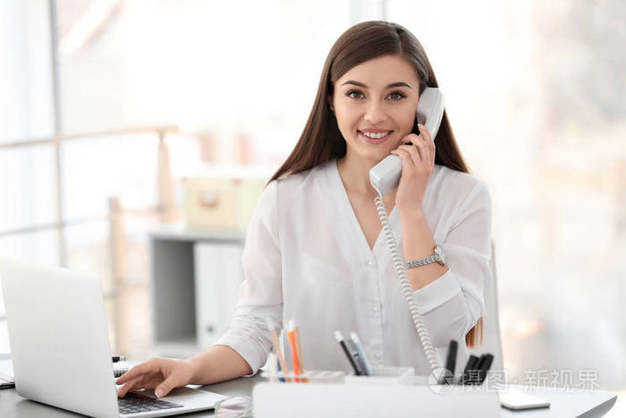在工作场所打电话的年轻女子