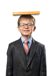 戴眼镜的小学生在一个白色的背景上拿着一本书在他的头上