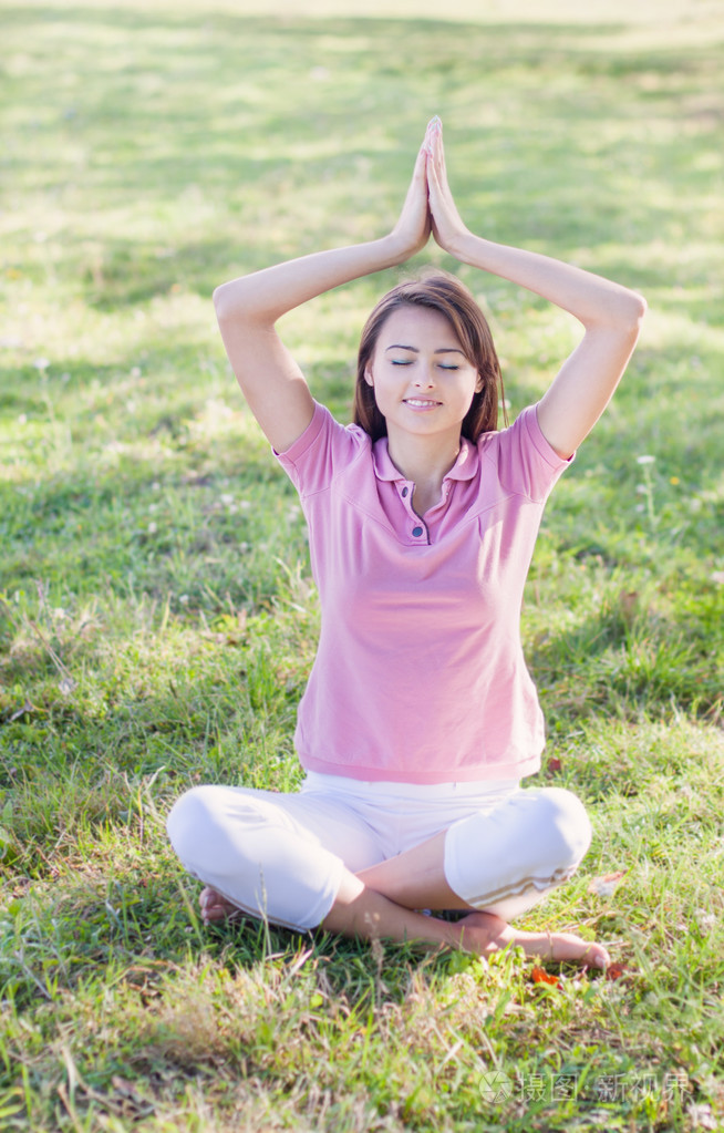 瑜伽女人在莲花在绿色草地上构成