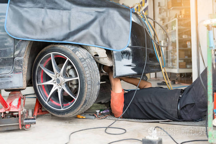 机修工躺在汽车中心的车下工作.概念机械修理车