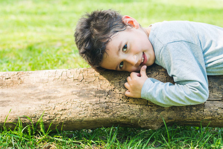 4岁的黑发男孩躺在原木上