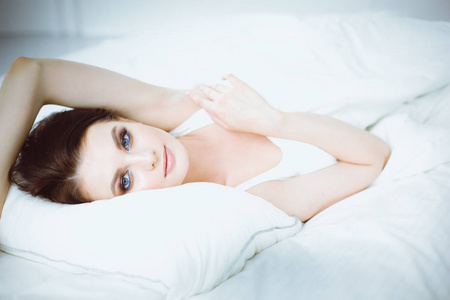 美丽的年轻妇女躺在白色的床上图片