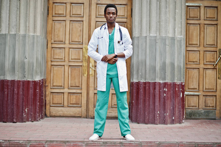 时髦的非洲裔美国人医生用听诊器和实验室外套被摆在对医院的门