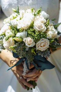 新娘捧着一束白色玫瑰新娘的花束