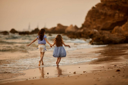 两姐妹抱着双手,去大海里的游泳.快乐的家庭度假的概念照片