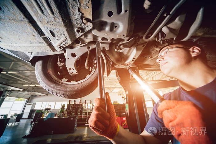 汽车修理工在维修服务站检查汽车吊架.背景