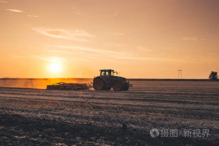 日落时拖拉机在大麦场上工作