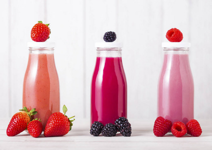玻璃瓶与新鲜的夏季浆果冰沙在木质背景。Strwberries 和 raspberies 蓝莓和黑莓