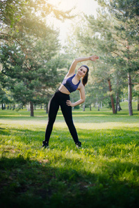 公园里的一个漂亮女孩从事体育运动。一种具有清洁皮肤和 oboyatelnoy ulvbkoy 的运动服装模型。露天培训