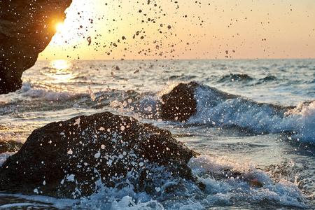 日落在海边。金砂。海浪在沙滩和岩石上翻滚