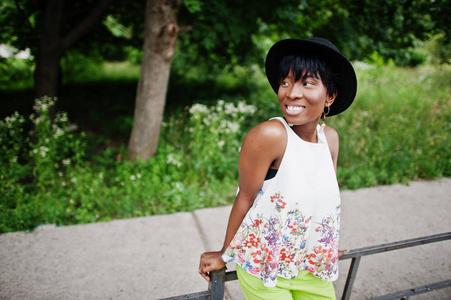 惊人的非洲裔美国模特在绿色的裤子和黑色的帽子摆在公园
