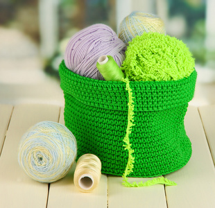 多彩纱针织用绿色窗口背景上的木桌上的篮子里