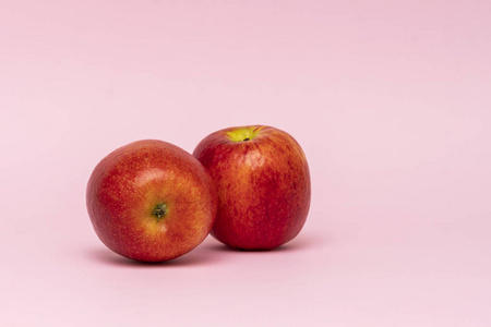 粉红色背景下的两个红色全苹果