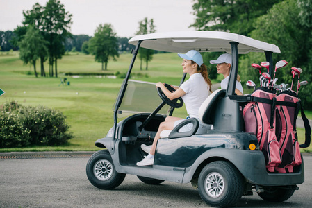 高尔夫球场骑高尔夫球车的女高尔夫球手侧面视图