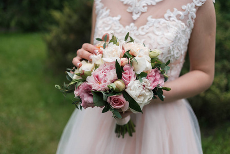 华丽的婚礼花束, 白色和粉红色的牡丹花, 玫瑰和绿叶在新娘的手中。婚礼花束新娘