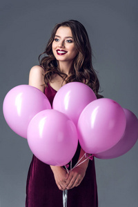 快乐的年轻妇女与束粉红色的气球, 在灰色隔离