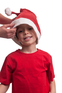 快乐的孩子被帮助他的母亲把他的圣诞老人帽子