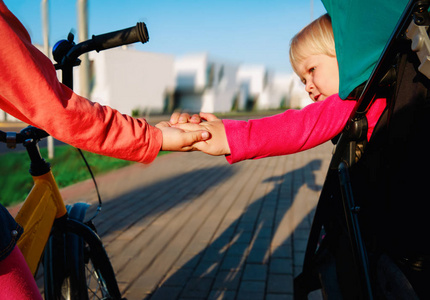 孩子们的信任和支持姐妹牵手在自行车和推车骑