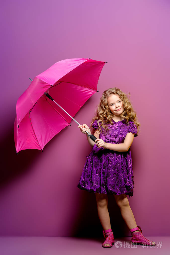 可爱的小女孩在一个美丽的夏季礼服与伞摆在工作室超过紫色背景.