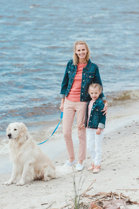 美丽的家庭走与金黄猎犬狗在海附近