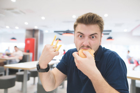 一个滑稽的情绪人与薯条, 而不是手指谁吃汉堡在快餐店和看相机。快餐概念