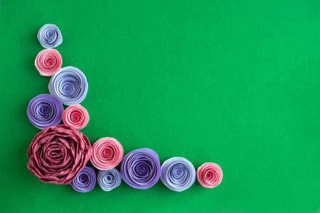 手工纸花的角度框架上的绿色背景。美丽的粉红色, 丁香, 紫色的纸玫瑰的角度形式。贺卡