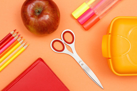 学校用品。彩色铅笔, 书, 苹果, 剪刀, 毛毡笔和午餐盒在粉红色的背景。顶部视图。回到学校的概念。粉彩色