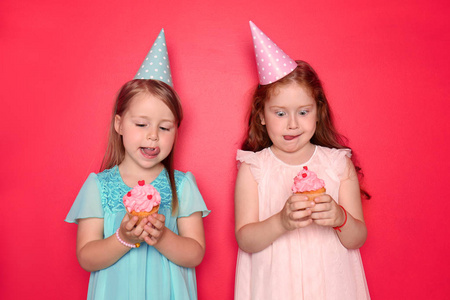 可爱的小女孩与生日帽子吃蛋糕的颜色背景