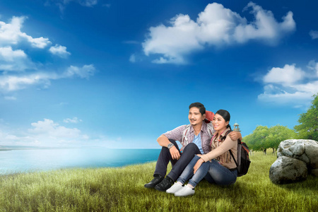 愉快的亚洲旅行者夫妇与背包享受海景与蓝天背景