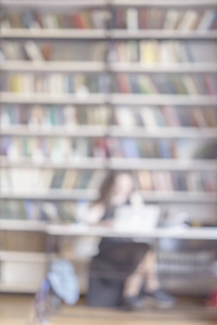 抽象模糊的女孩阅读笔记本电脑在公共图书馆, 高柜, 书柜, 许多书籍, 垂直背景。学习教育的概念