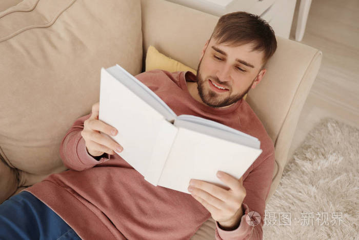 家中躺在沙发上的年轻人看书