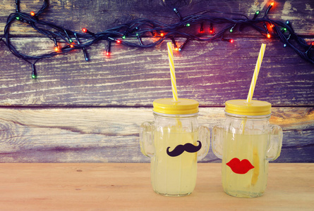 新鲜柠檬水饮料的形象在可爱的仙人掌形状的眼镜戴着胡子和嘴唇, 在木桌上。热带夏日浪漫假期概念