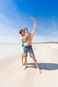 年轻的夫妇在海滩采取与移动的自画像