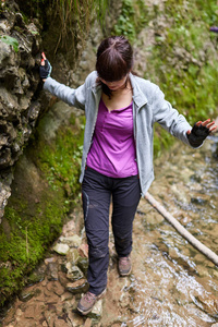 横跨河的年轻妇女徒步旅行者峡谷