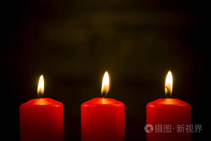 在黑暗背景下点燃三根红色蜡烛照片-正版商用图片061ckz-摄图新视界